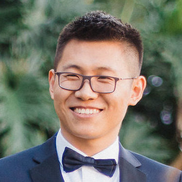 A headshot of Xin (Eric) Wang, a man wearing a black suit and bow tie with short black hair, looking directly at the camera smiling.